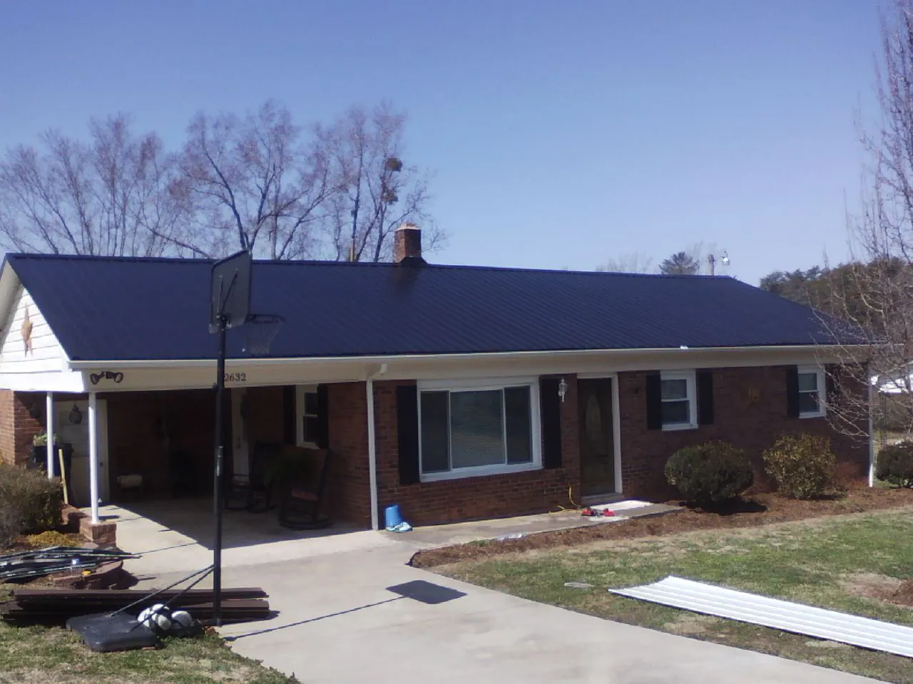 Finished dark blue metal roof on a brick ranch with a carport in East Bernard