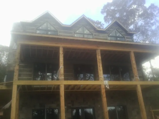 Dormers and porch framing on a large log home under construction — Roof Coating work by our crew in East Bernard