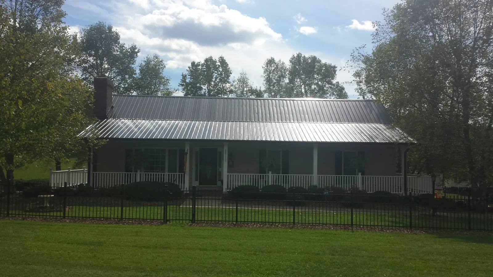 Gray metal roof on a brick ranch with a full width front porch — Gutter Guard Installation work by our crew in East Bernard