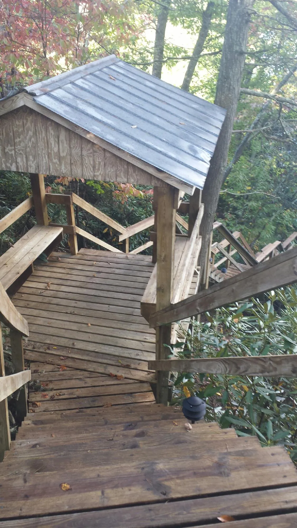 Metal roofed shelter over wooden steps on a wooded walkway — Skylight Repair & Installation work by our crew in East Bernard