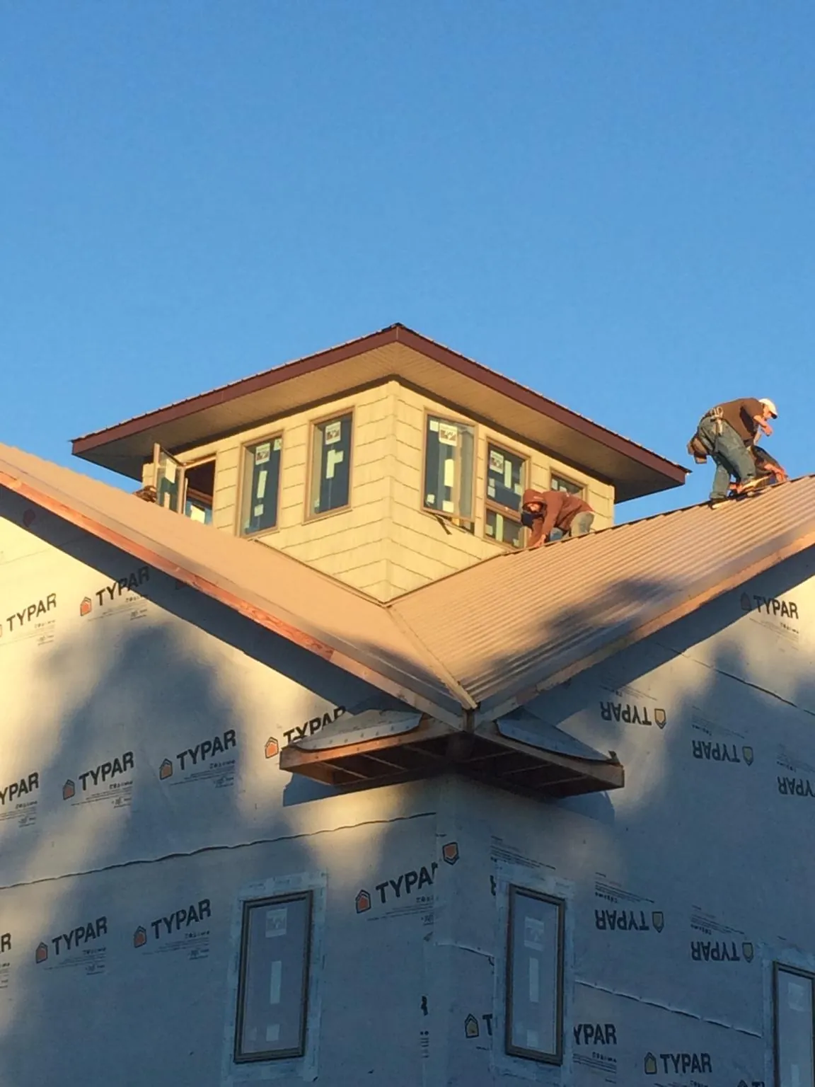 Roofers working around a rooftop cupola on a new metal roof at sunset — Roof Waterproofing in East Bernard by Roofing Brothers
